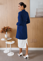 Vista posterior do jaleco feminino azul-marinho em jacquard floral, mostrando a modelagem alongada, as mangas compridas e o caimento das costas.